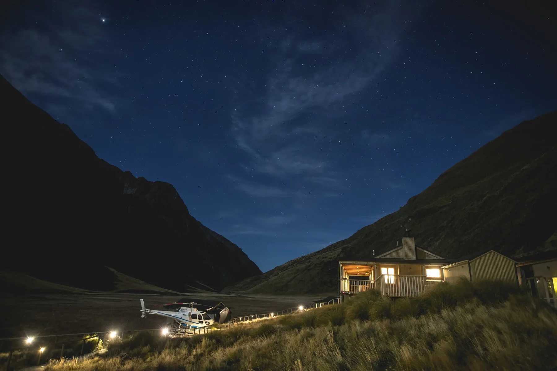 Minaret Station alpine lodge lit at dusk beneath the Southern Alps