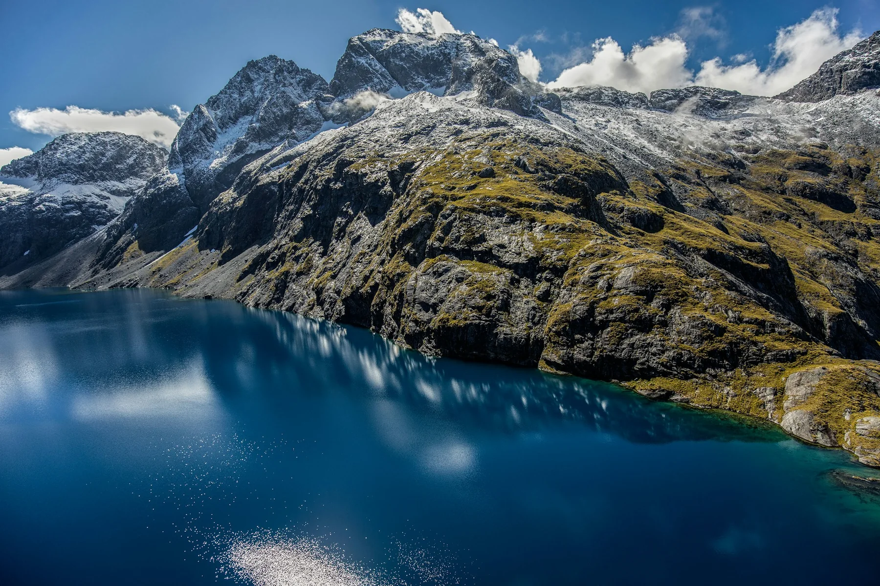 Calm Fiordland water with forested mountains rising from the shore